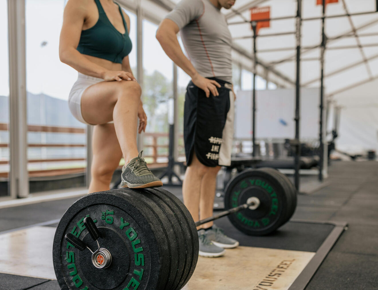 Man and woman standing in front of weights in gym.